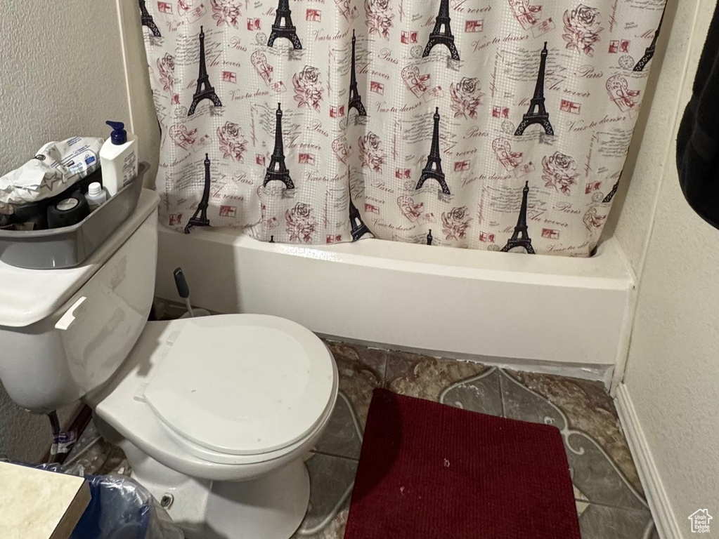 Bathroom featuring toilet, shower / bath combo with shower curtain, vanity, and a textured wall