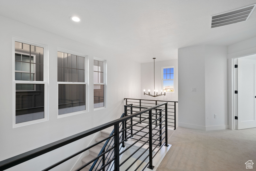 Hallway featuring an upstairs landing, a chandelier, carpet floors, and recessed lighting