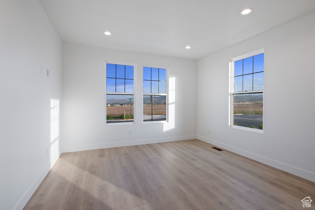 Empty room featuring healthy amount of natural light, wood finished floors, and recessed lighting