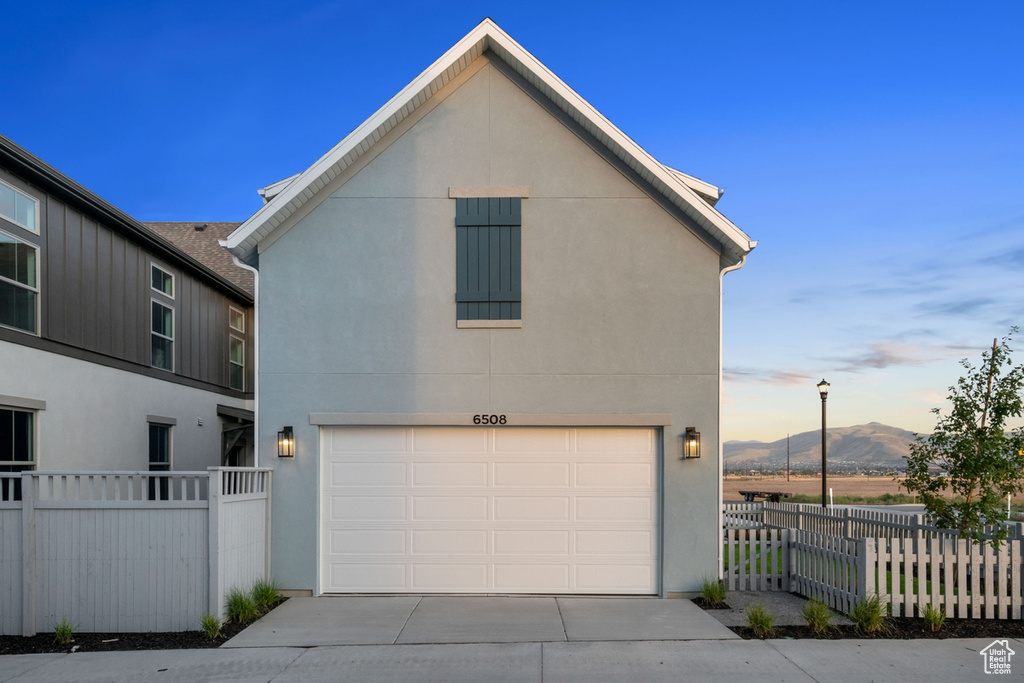 View of front of property featuring a garage, driveway, stucco siding, and a mountain view