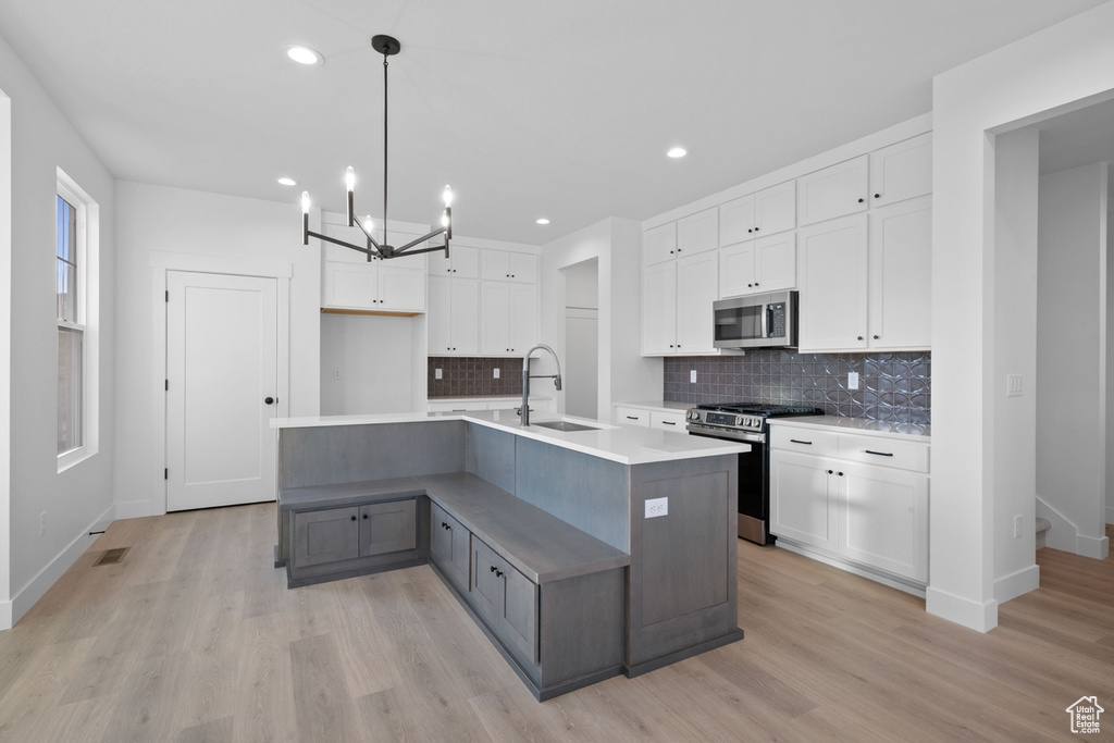 Kitchen featuring stainless steel appliances, white cabinetry, tasteful backsplash, light wood finished floors, and recessed lighting