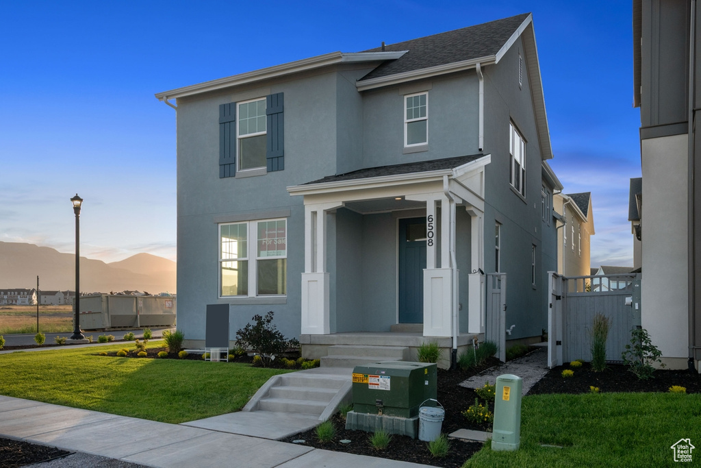 View of front of property featuring stucco siding, a lawn, and a mountain view
