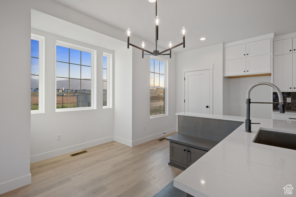 Kitchen featuring a chandelier, light wood finished floors, white cabinets, recessed lighting, and light countertops