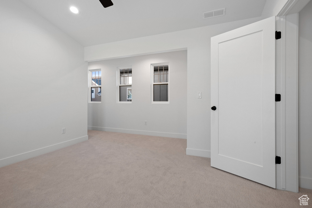 Empty room with light colored carpet and recessed lighting