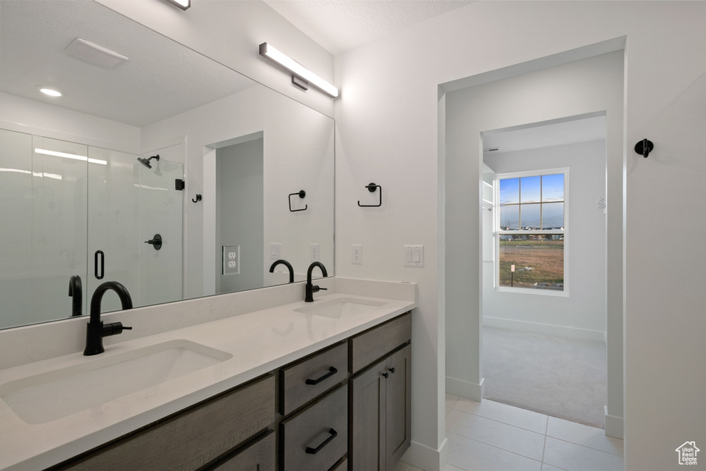Bathroom with double vanity, tile patterned floors, and a stall shower