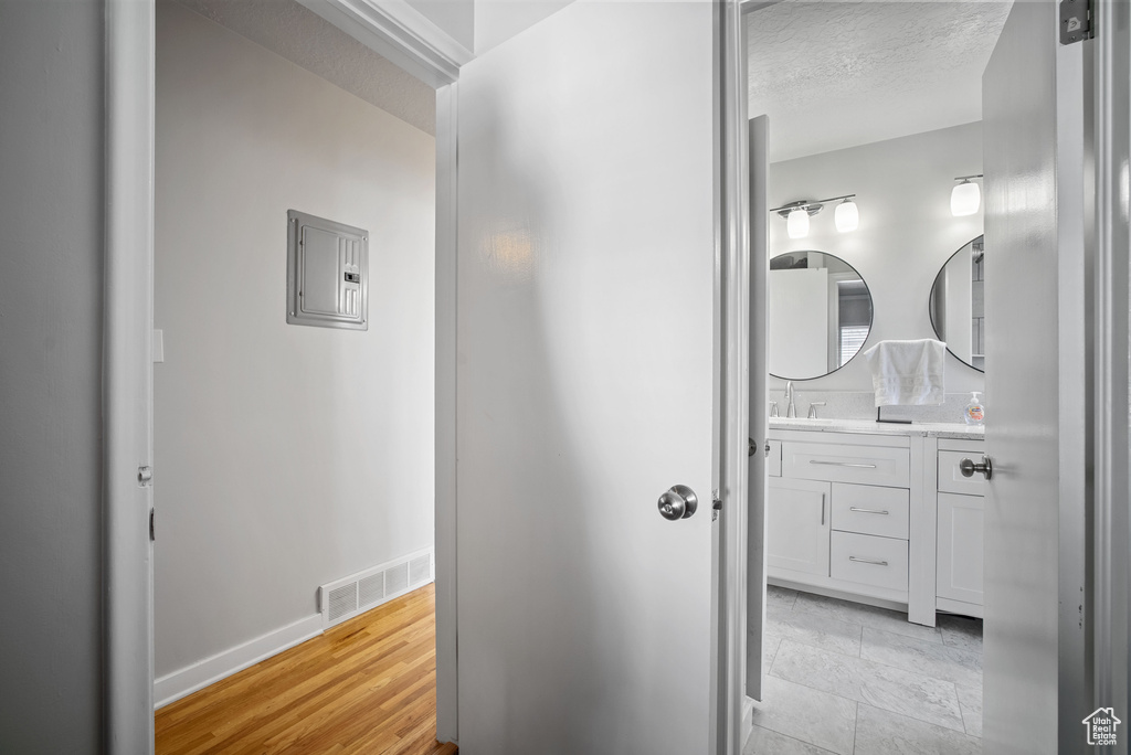 Hallway featuring electric panel and baseboards