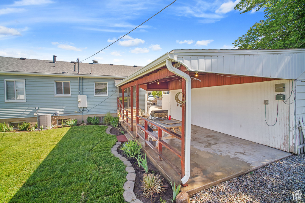 View of green lawn featuring central AC and an attached carport