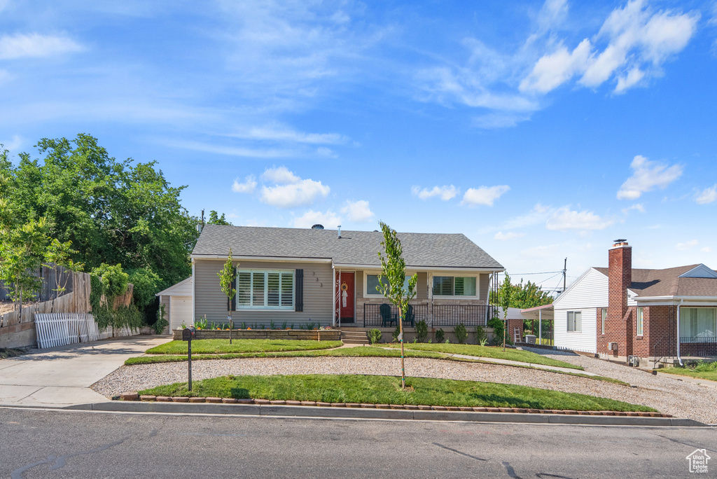 View of front of house with concrete driveway, a fenced front yard, and a garage