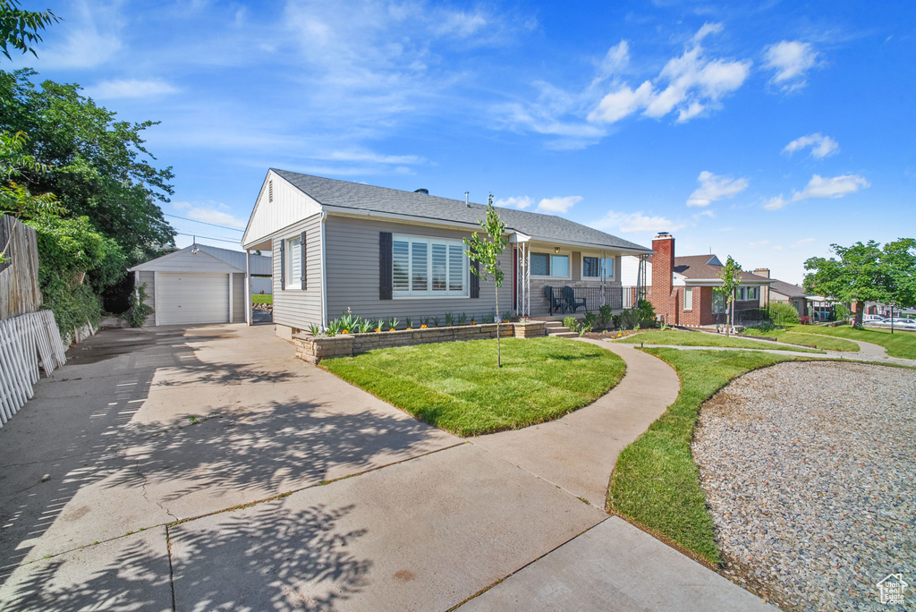 View of front of home featuring an outdoor structure, a garage, a front yard, and concrete driveway