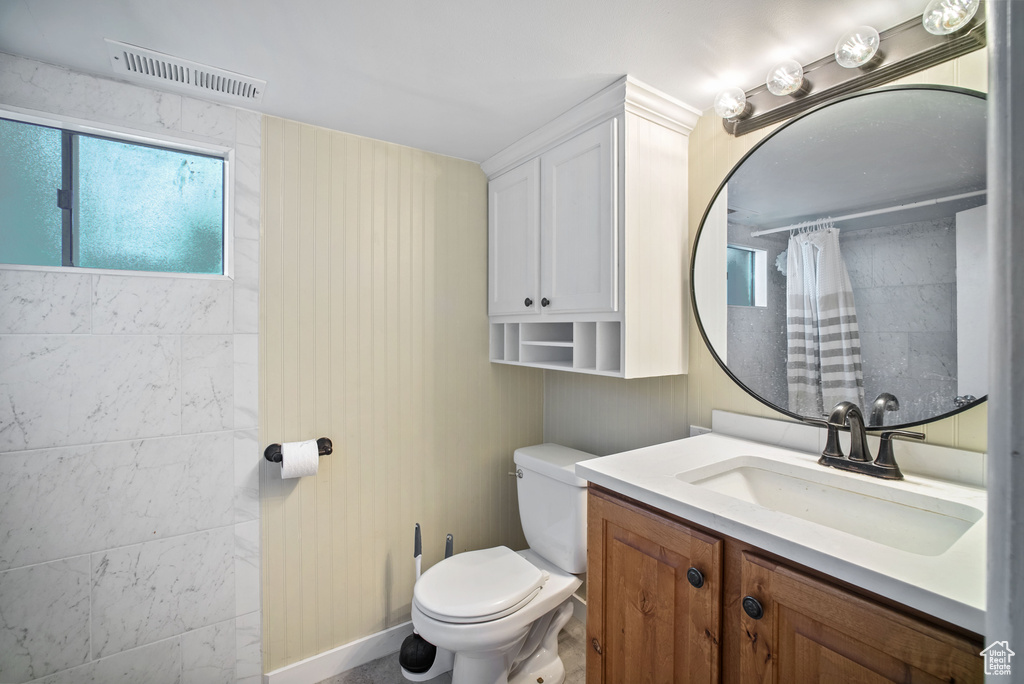 Bathroom featuring vanity, toilet, and tiled shower