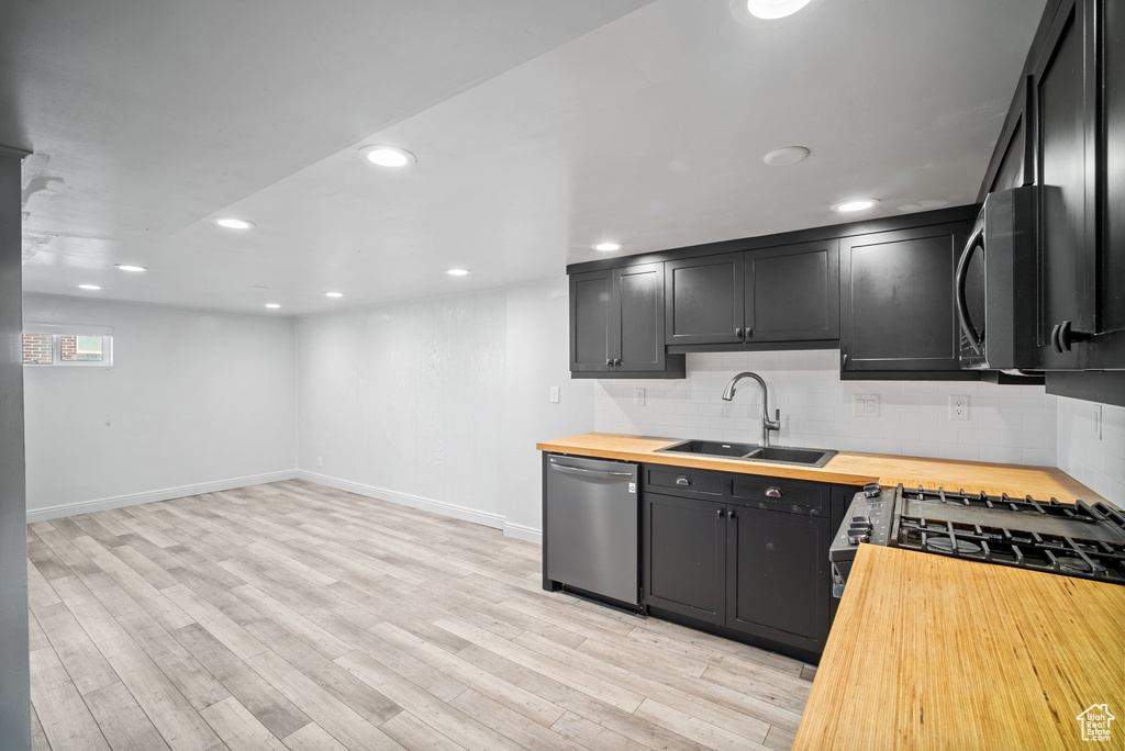 Kitchen with wooden counters, a sink, dishwasher, backsplash, and recessed lighting