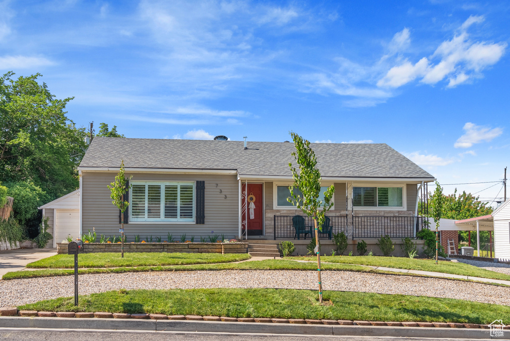 Single story home with a porch, a front lawn, a garage, and driveway