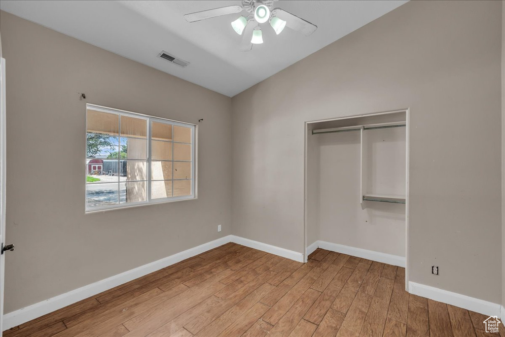 Unfurnished bedroom featuring vaulted ceiling, wood finished floors, a closet, and ceiling fan