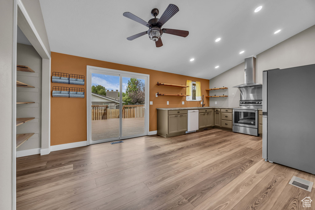 Kitchen featuring appliances with stainless steel finishes, wall chimney exhaust hood, open shelves, vaulted ceiling, and light wood-style floors