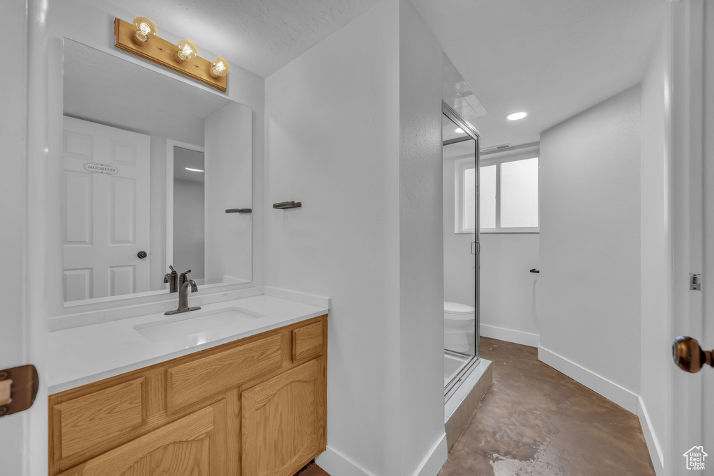 Bathroom with concrete flooring, a shower stall, vanity, and recessed lighting
