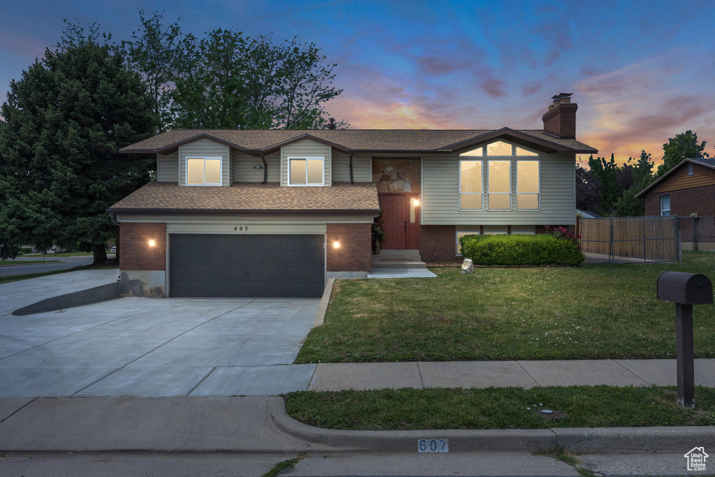 Raised ranch featuring a garage, driveway, and a chimney