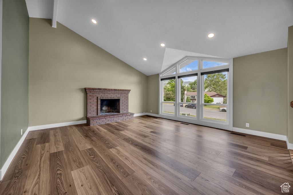 Unfurnished living room with wood finished floors, a brick fireplace, and recessed lighting
