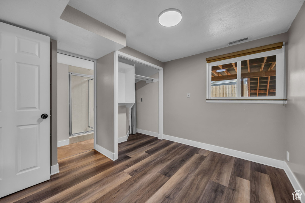 Unfurnished bedroom with dark wood-style floors and a closet