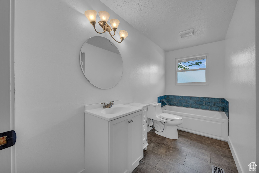 Bathroom with vanity, a bath, a textured ceiling, and a chandelier