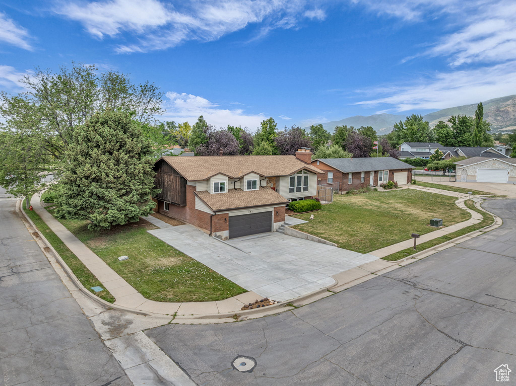View of front of property featuring a front lawn, driveway, brick siding, and a mountain view