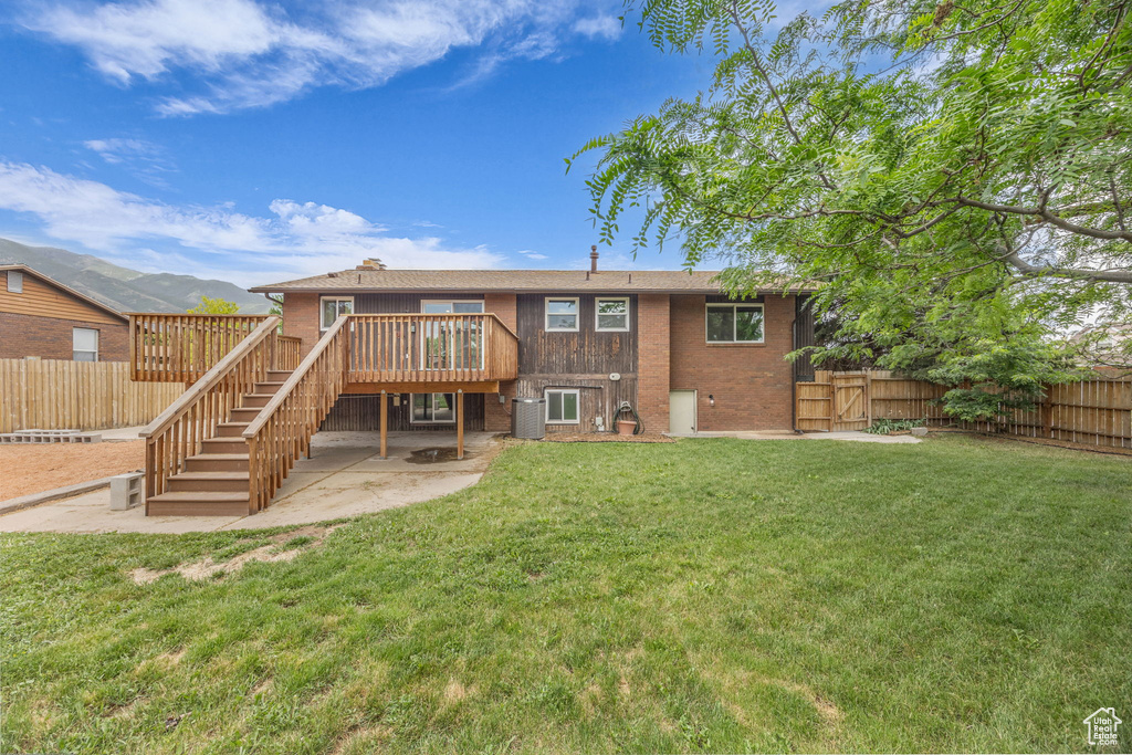 Rear view of property with stairway, a fenced backyard, a wooden deck, and a patio area