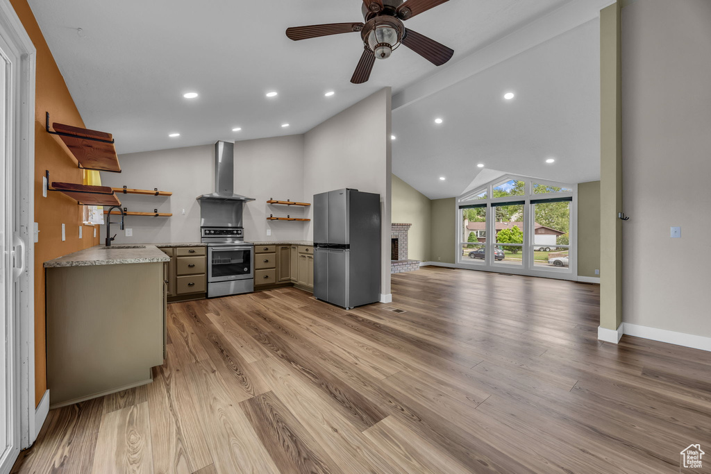 Kitchen with open shelves, appliances with stainless steel finishes, wall chimney range hood, open floor plan, and ceiling fan