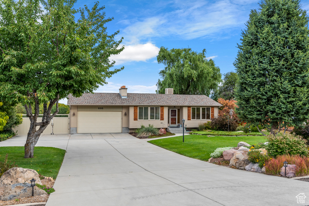Single story home featuring a chimney, an attached garage, and driveway
