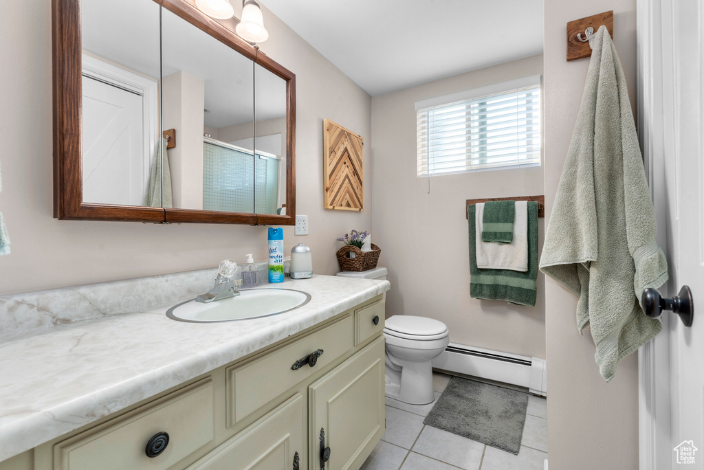 Full bathroom with a baseboard heating unit, vanity, tile patterned flooring, and an enclosed shower
