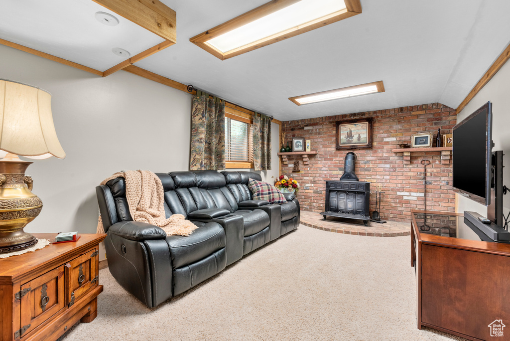 Carpeted living room with a wood stove, brick wall, and lofted ceiling