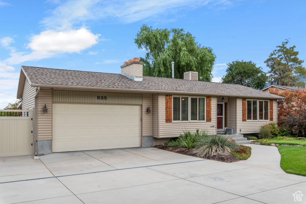 Ranch-style house featuring a chimney, a garage, and driveway