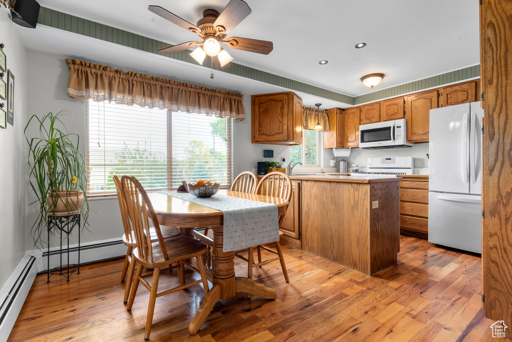 Kitchen featuring white appliances, a peninsula, a baseboard radiator, healthy amount of natural light, and recessed lighting