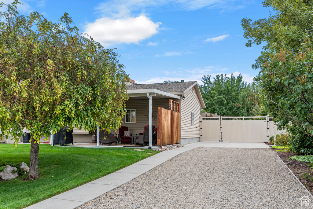 View of front of home with a gate, a patio area, and driveway