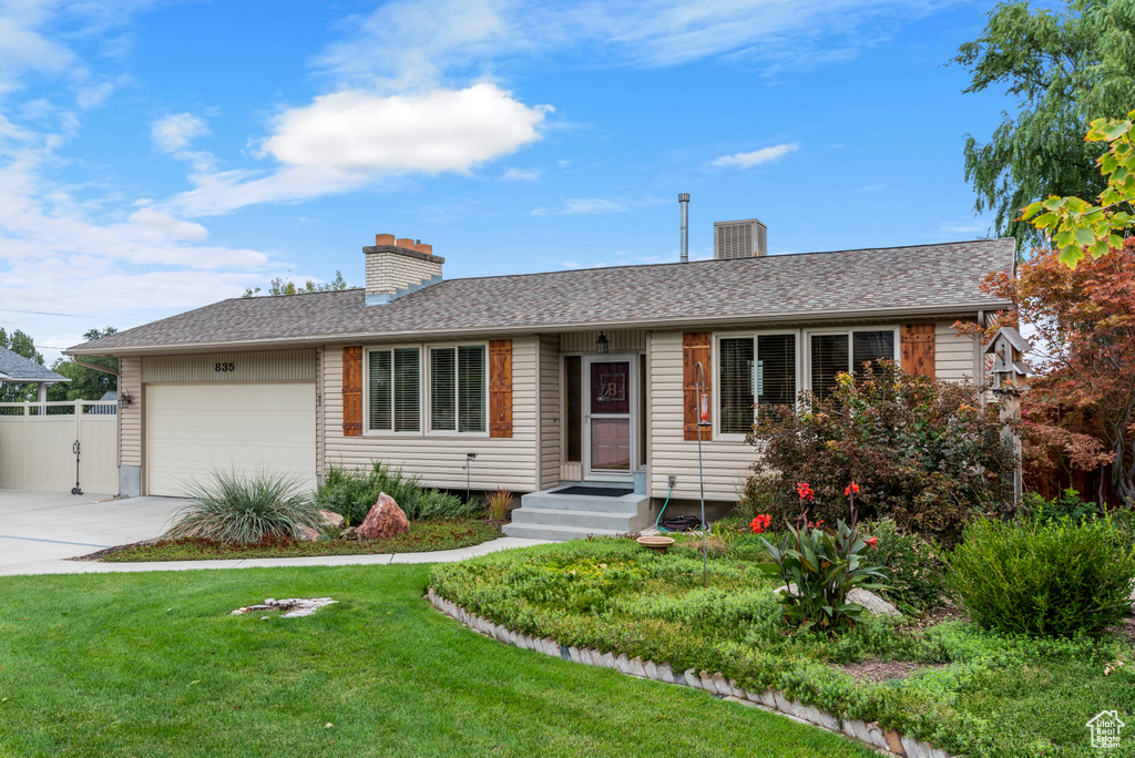 Single story home featuring a chimney, an attached garage, and concrete driveway