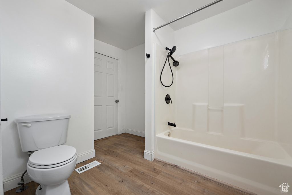 Full bathroom featuring wood finished floors and washtub / shower combination