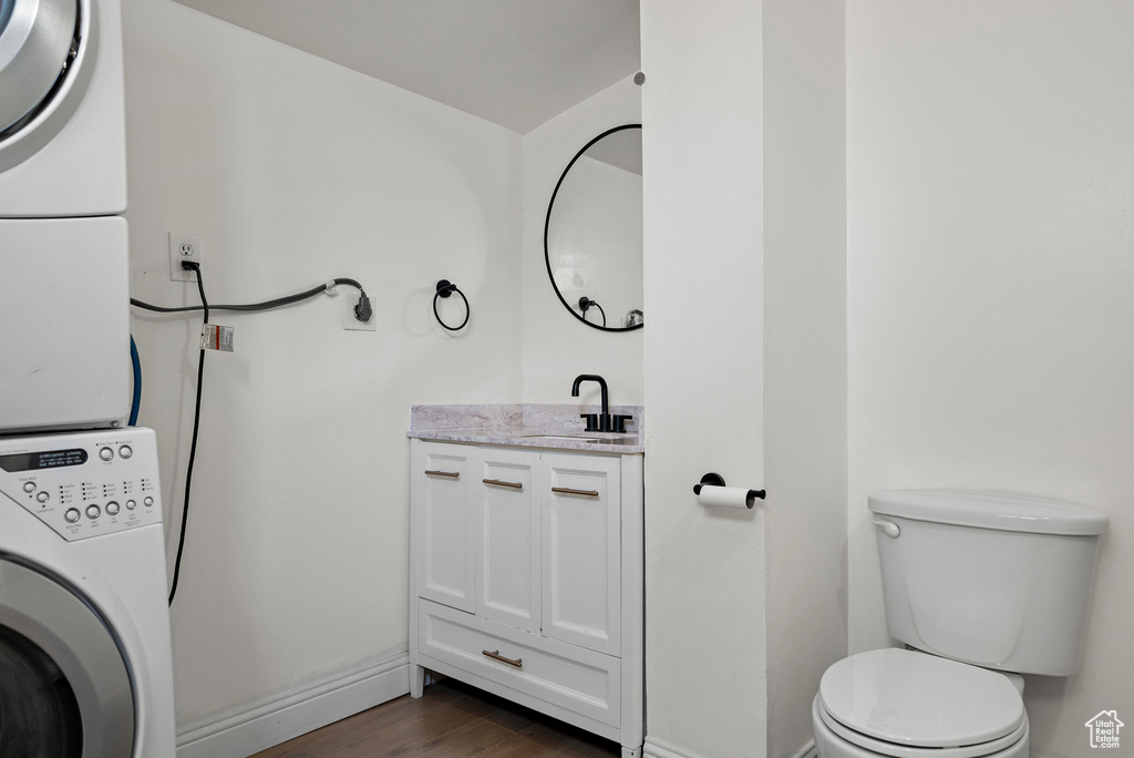 Half bath featuring estacked washer and dryer, vanity, and wood finished floors