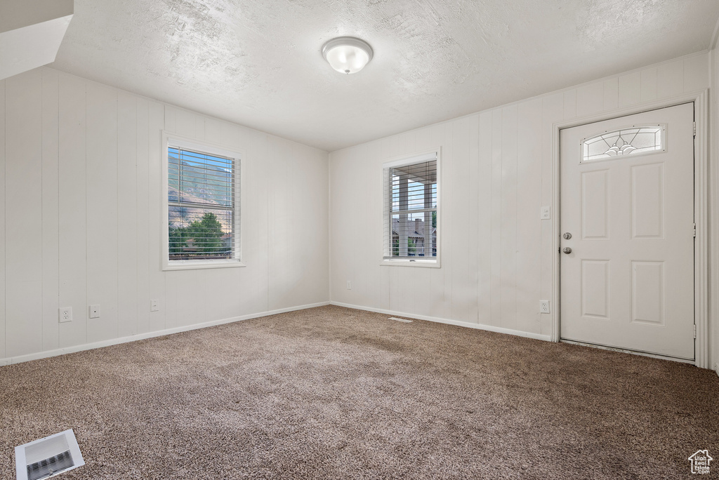 Carpeted entryway with a textured ceiling and baseboards