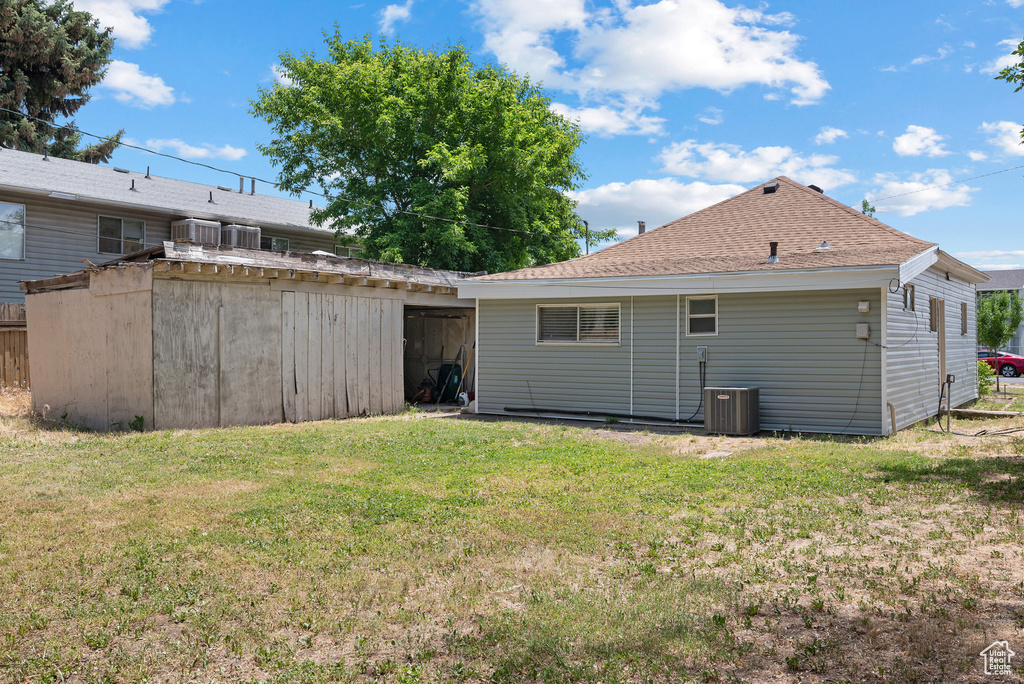 Rear view of house featuring a yard and roof with shingles