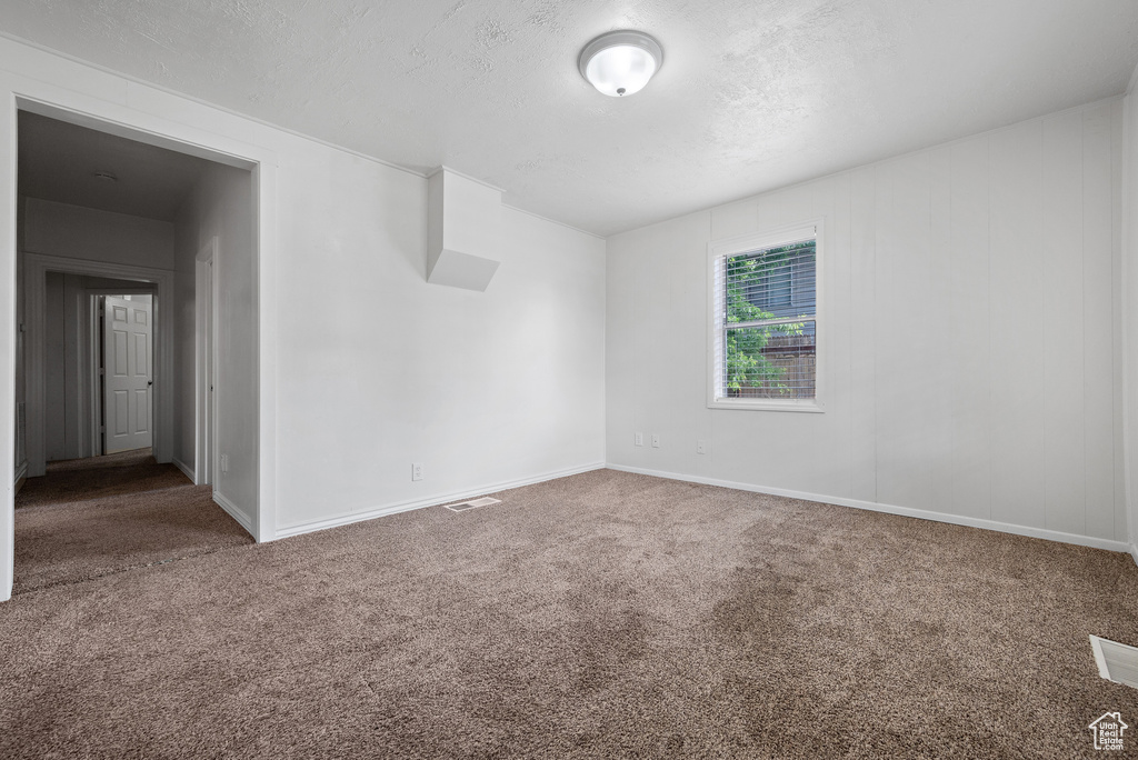 Unfurnished room featuring carpet flooring and a textured ceiling
