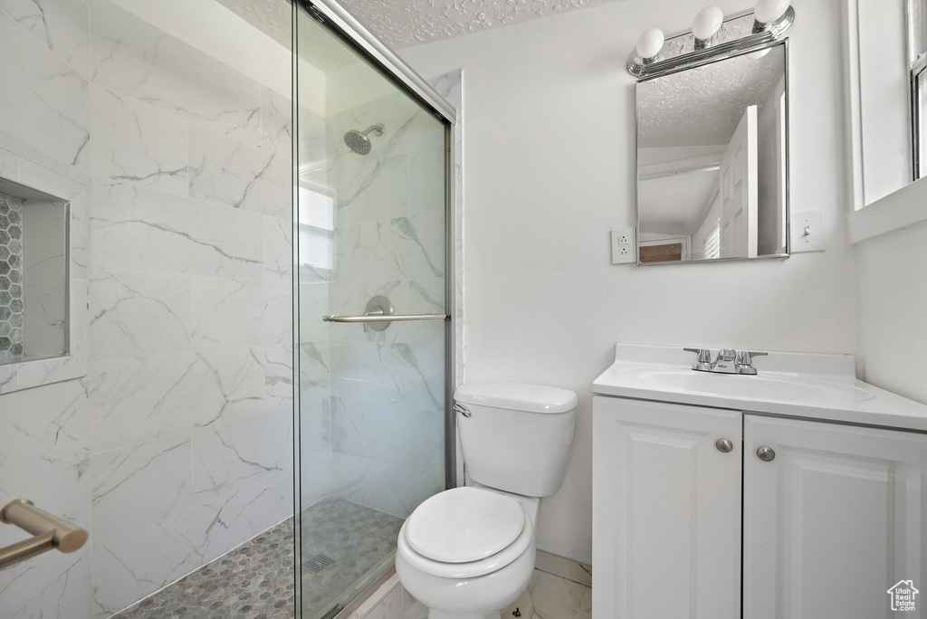 Full bath with a marble finish shower, vanity, and a textured ceiling