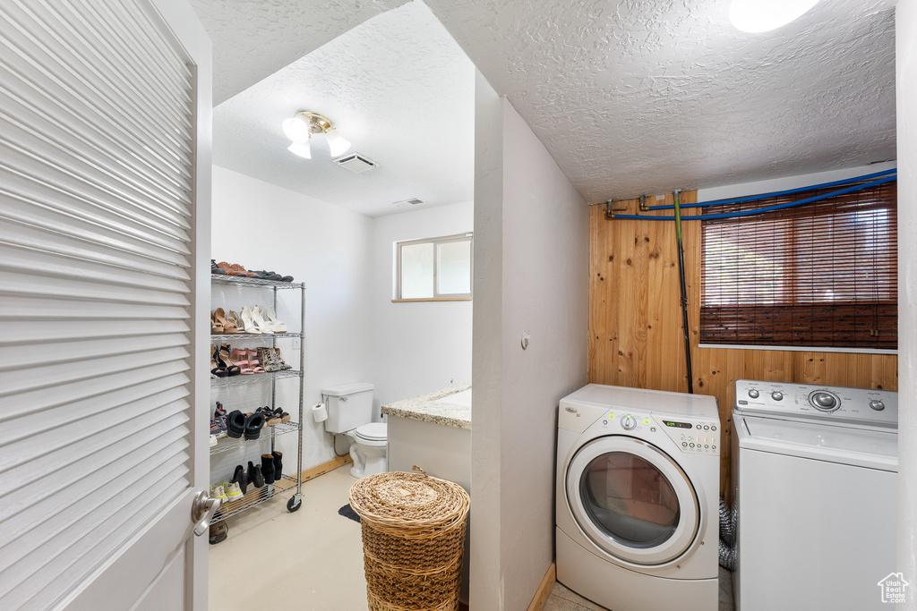 Washroom with washing machine and dryer and a textured ceiling
