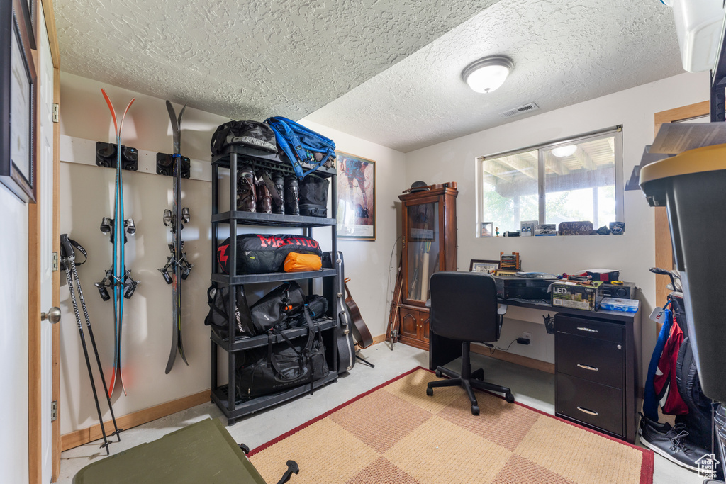 Office area with baseboards, a textured ceiling, and light flooring