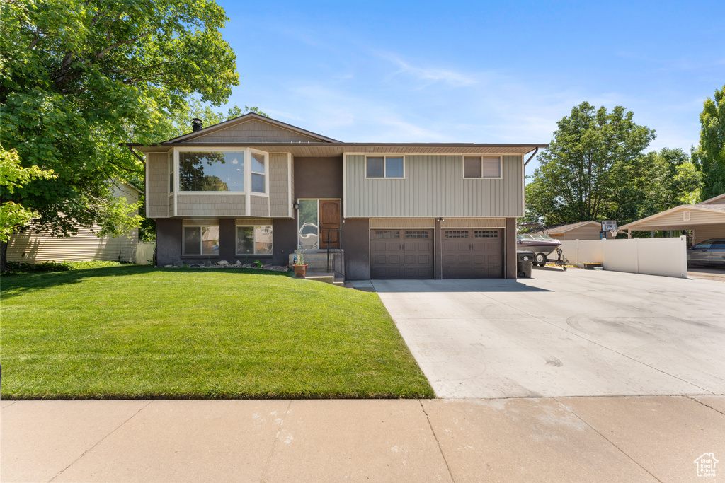 Raised ranch featuring an attached garage and concrete driveway