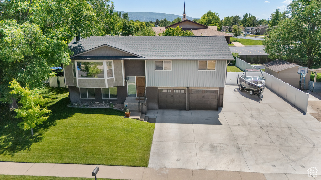 Split foyer home with driveway, roof with shingles, and a garage