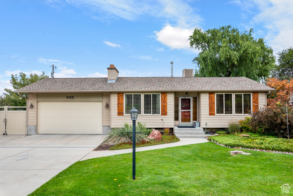 Ranch-style house with an attached garage, concrete driveway, and a chimney