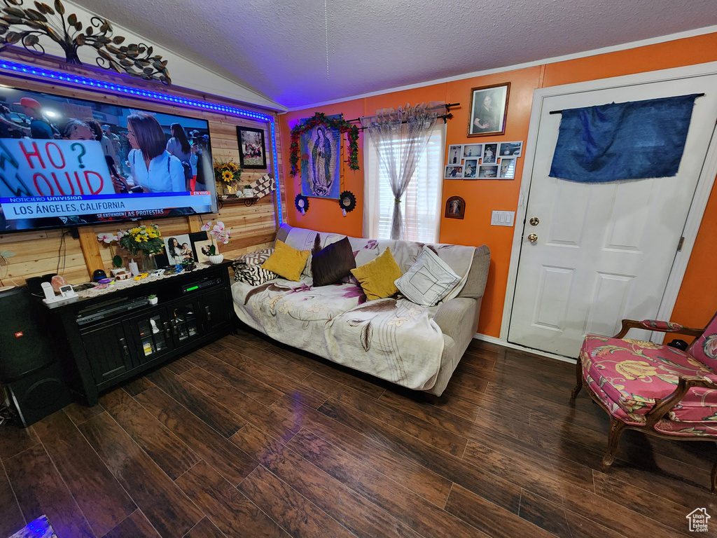 Living room with lofted ceiling, hardwood / wood-style flooring, and a textured ceiling