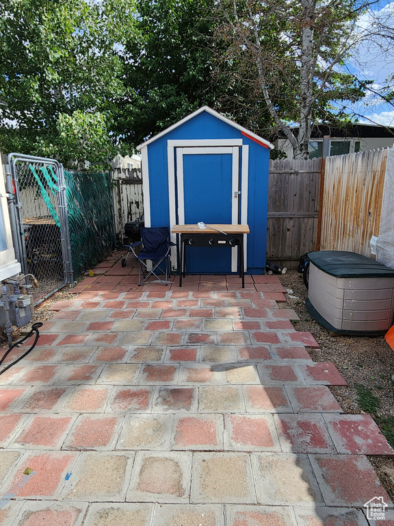 Fenced backyard featuring a storage unit and a patio area