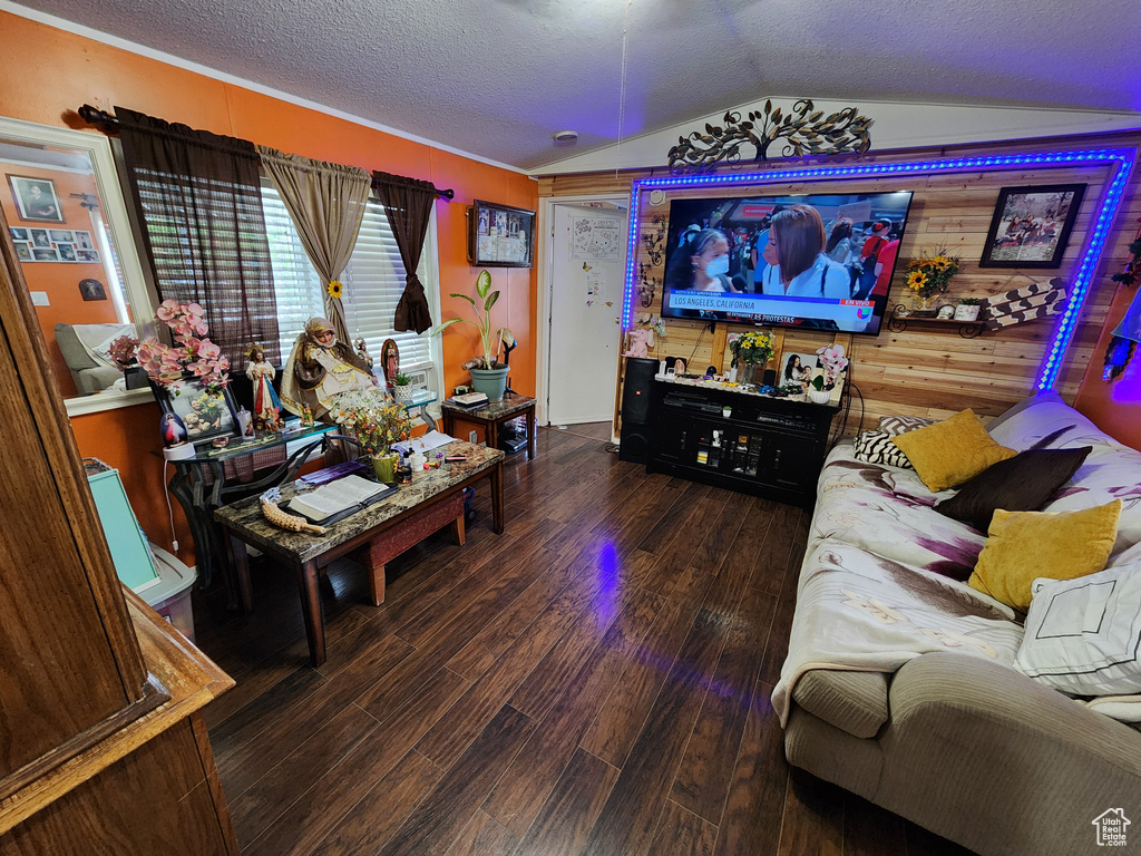 Living area featuring vaulted ceiling, wood finished floors, and a textured ceiling