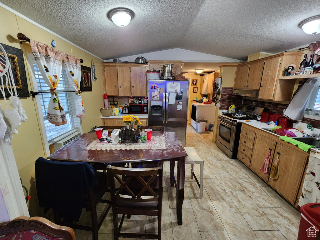 Kitchen featuring stainless steel appliances, vaulted ceiling, under cabinet range hood, a textured ceiling, and open shelves
