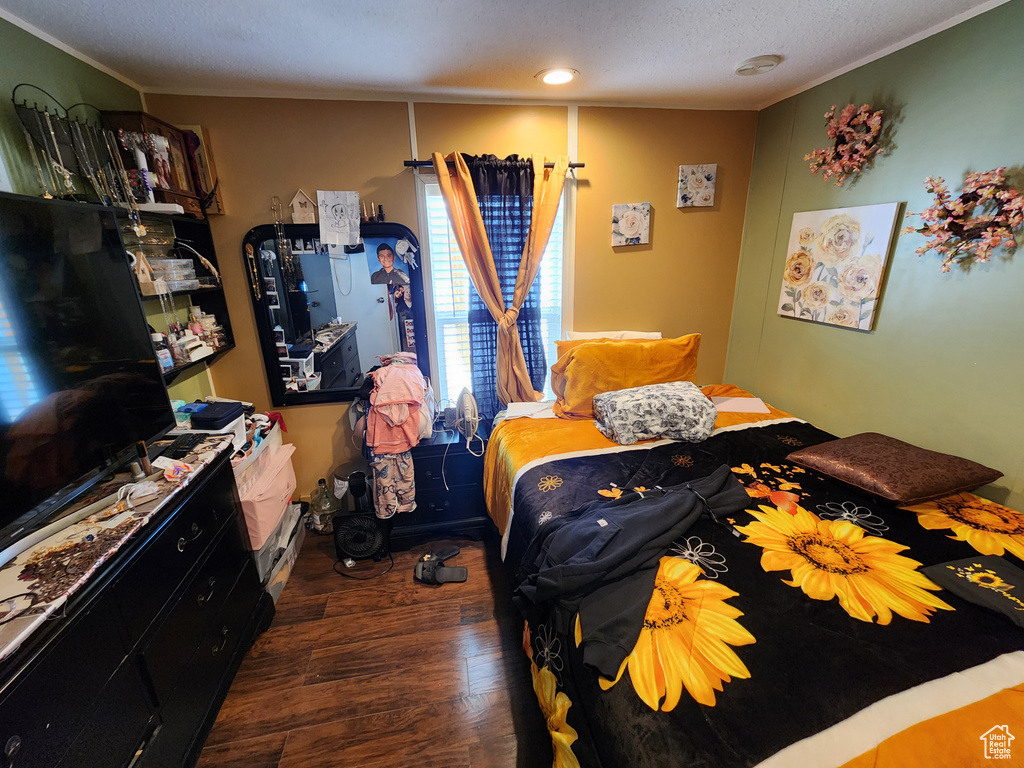 Bedroom featuring wood finished floors, ornamental molding, and a textured ceiling