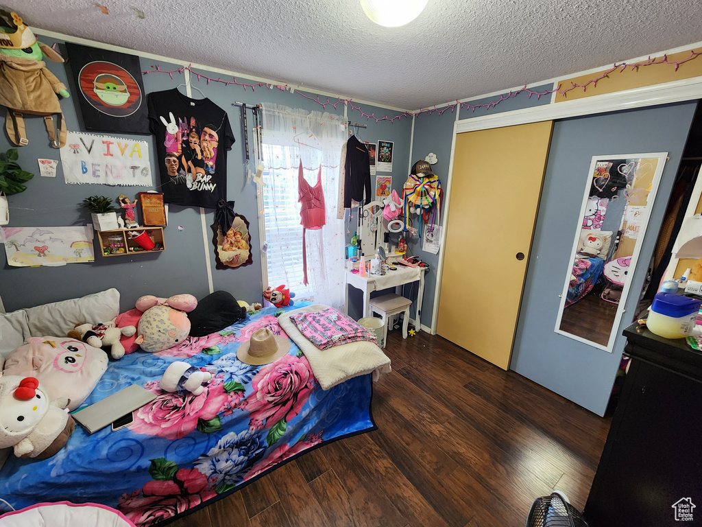 Bedroom with a textured ceiling, wood finished floors, and a closet